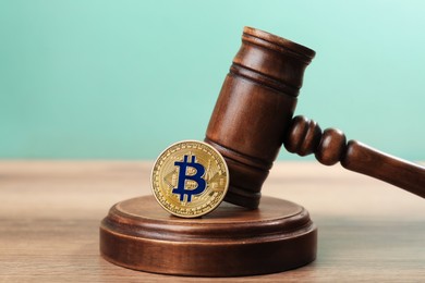 Photo of Cryptocurrency. Bitcoin and judge's gavel on wooden table, closeup