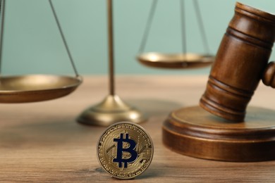 Photo of Cryptocurrency. Bitcoin, judge's gavel and scales on wooden table, closeup