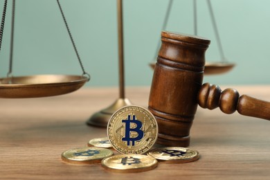 Photo of Cryptocurrency. Bitcoins, judge's gavel and scales on wooden table, closeup
