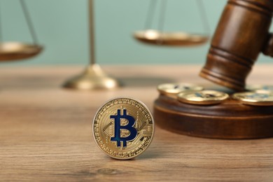 Photo of Cryptocurrency. Bitcoins, judge's gavel and scales on wooden table, closeup