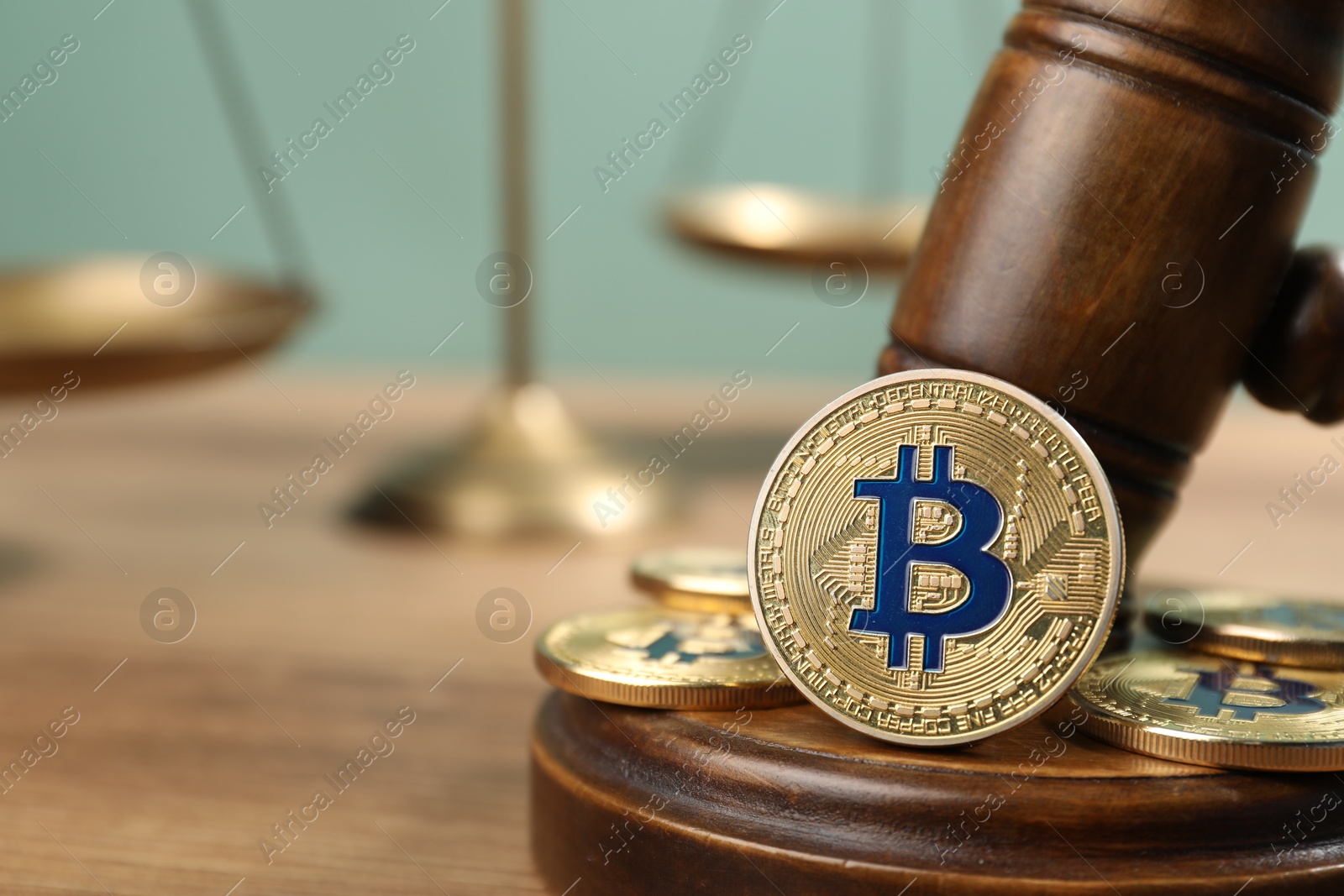Photo of Cryptocurrency. Bitcoins, judge's gavel and scales on wooden table, closeup. Space for text
