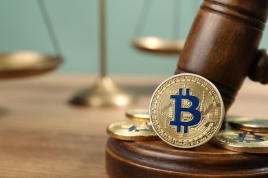Photo of Cryptocurrency. Bitcoins, judge's gavel and scales on wooden table, closeup. Space for text