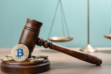 Photo of Cryptocurrency. Bitcoins, judge's gavel and scales on wooden table, closeup