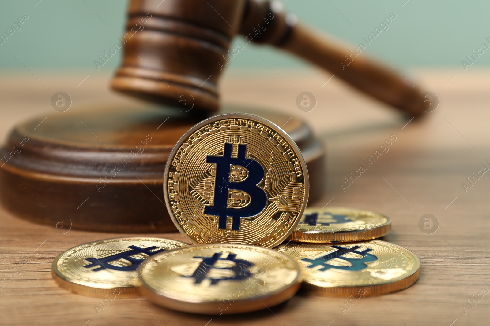 Cryptocurrency. Bitcoins and judge's gavel on wooden table, closeup Photo of Cryptocurrency. Bitcoins and judge's gavel on wooden table, closeup