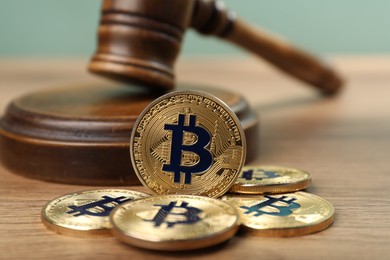 Photo of Cryptocurrency. Bitcoins and judge's gavel on wooden table, closeup