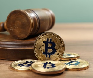 Photo of Cryptocurrency. Bitcoins and judge's gavel on wooden table, closeup