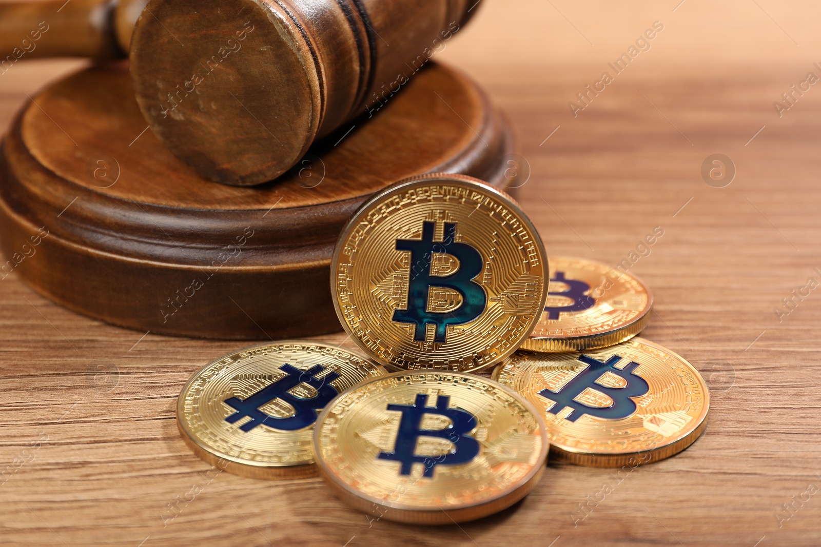 Cryptocurrency. Bitcoins and judge's gavel on wooden table, closeup Photo of Cryptocurrency. Bitcoins and judge's gavel on wooden table, closeup