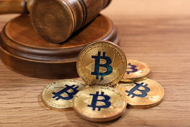Photo of Cryptocurrency. Bitcoins and judge's gavel on wooden table, closeup