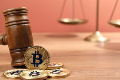 Photo of Cryptocurrency. Bitcoins, judge's gavel and scales on wooden table, closeup. Space for text