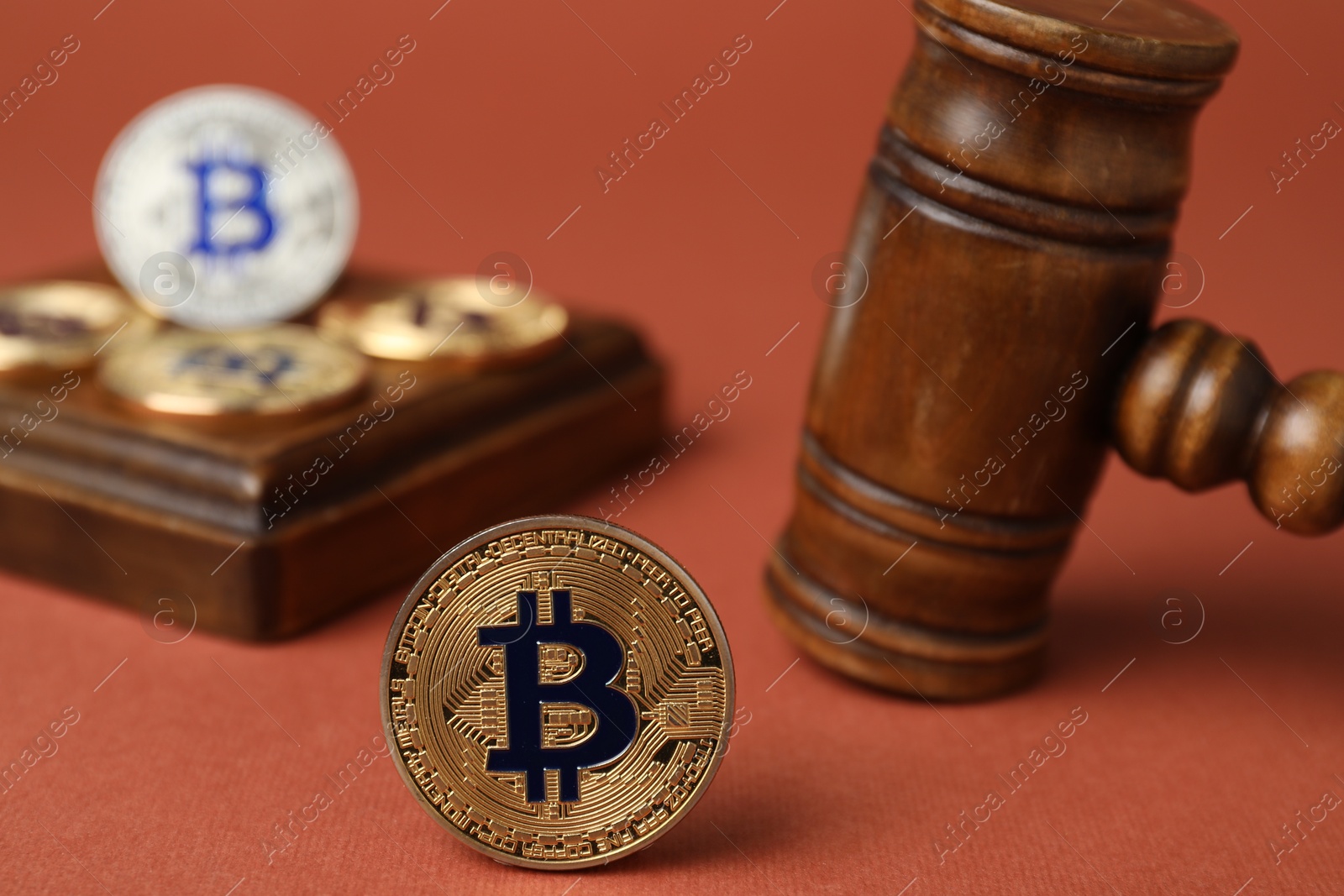 Photo of Cryptocurrency. Bitcoins and judge's gavel on red-brown background, closeup