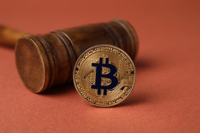 Photo of Cryptocurrency. Bitcoin and judge's gavel on red-brown background, closeup