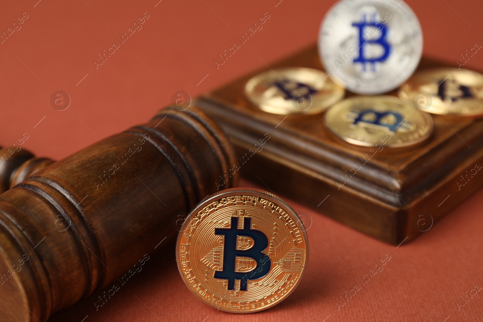 Photo of Cryptocurrency. Bitcoins and judge's gavel on red-brown background, closeup