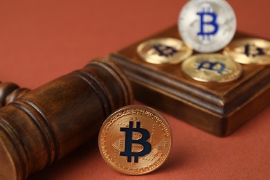 Photo of Cryptocurrency. Bitcoins and judge's gavel on red-brown background, closeup