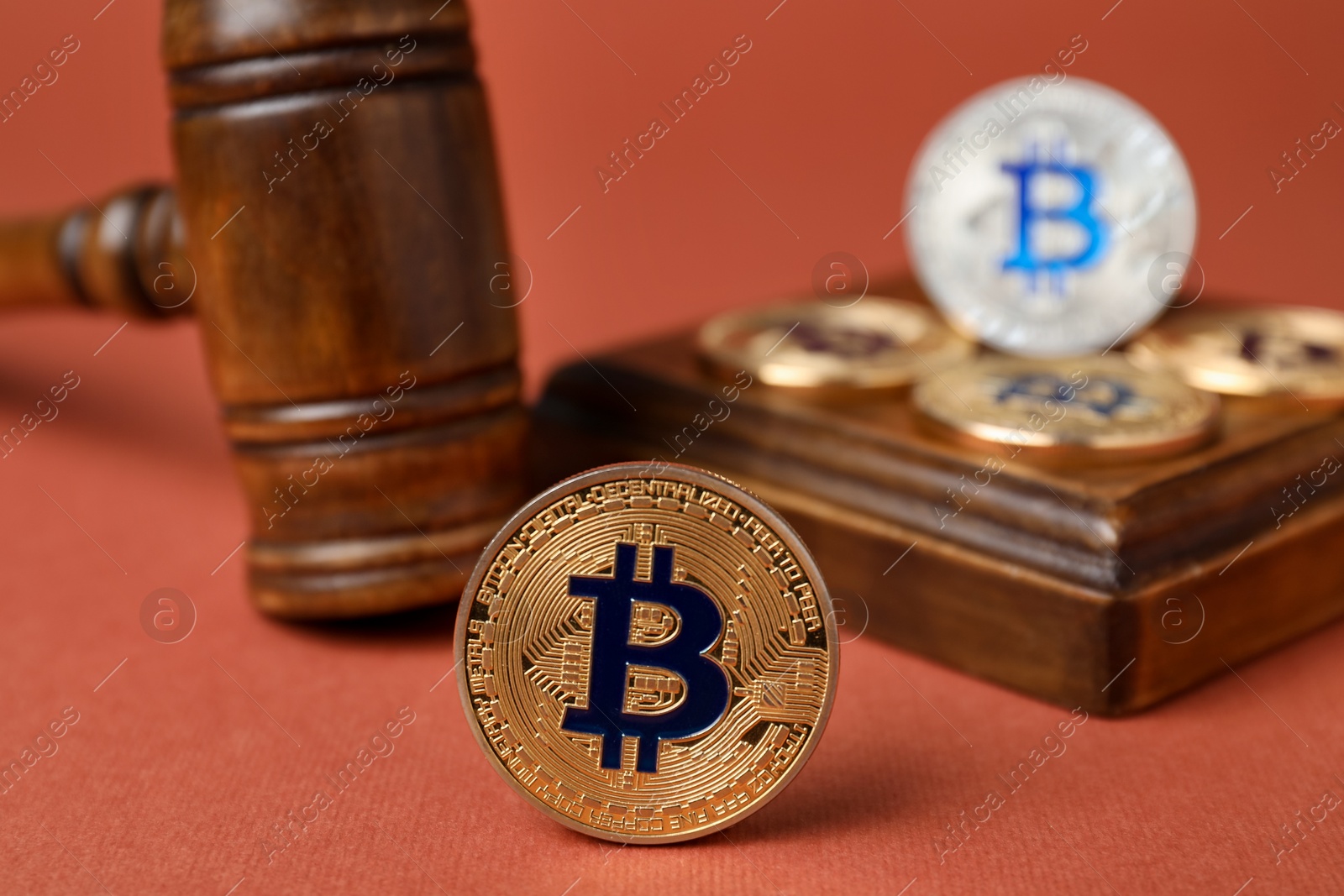 Photo of Cryptocurrency. Bitcoins and judge's gavel on red-brown background, closeup