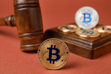 Photo of Cryptocurrency. Bitcoins and judge's gavel on red-brown background, closeup