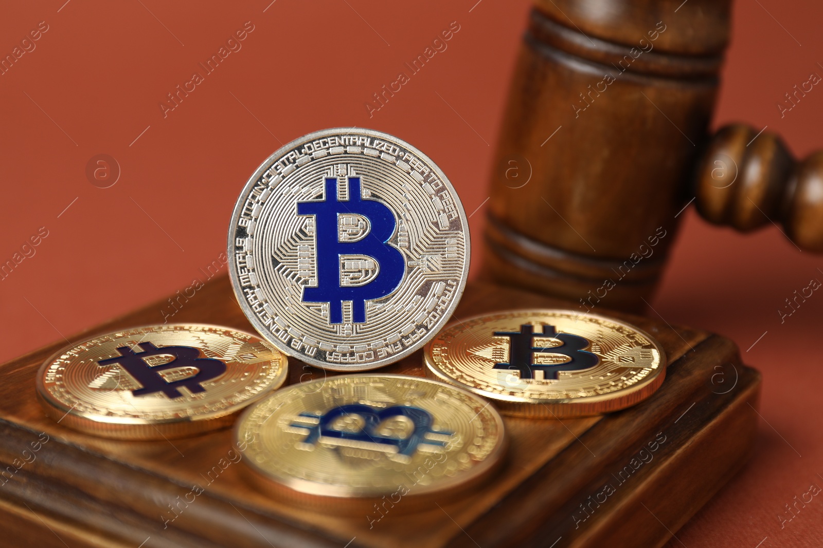 Photo of Cryptocurrency. Bitcoins and judge's gavel on red-brown background, closeup