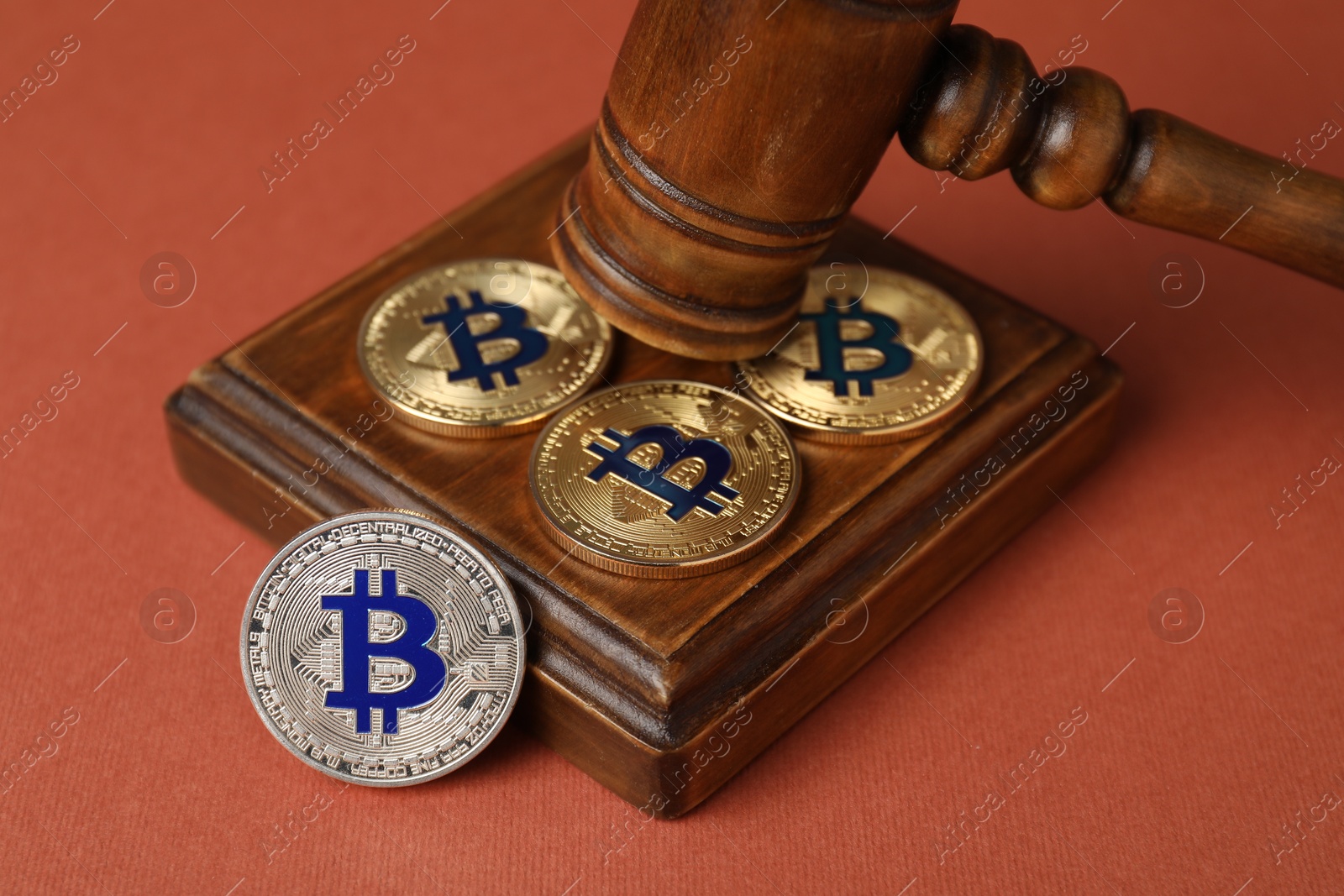 Photo of Cryptocurrency. Bitcoins and judge's gavel on red-brown background, closeup