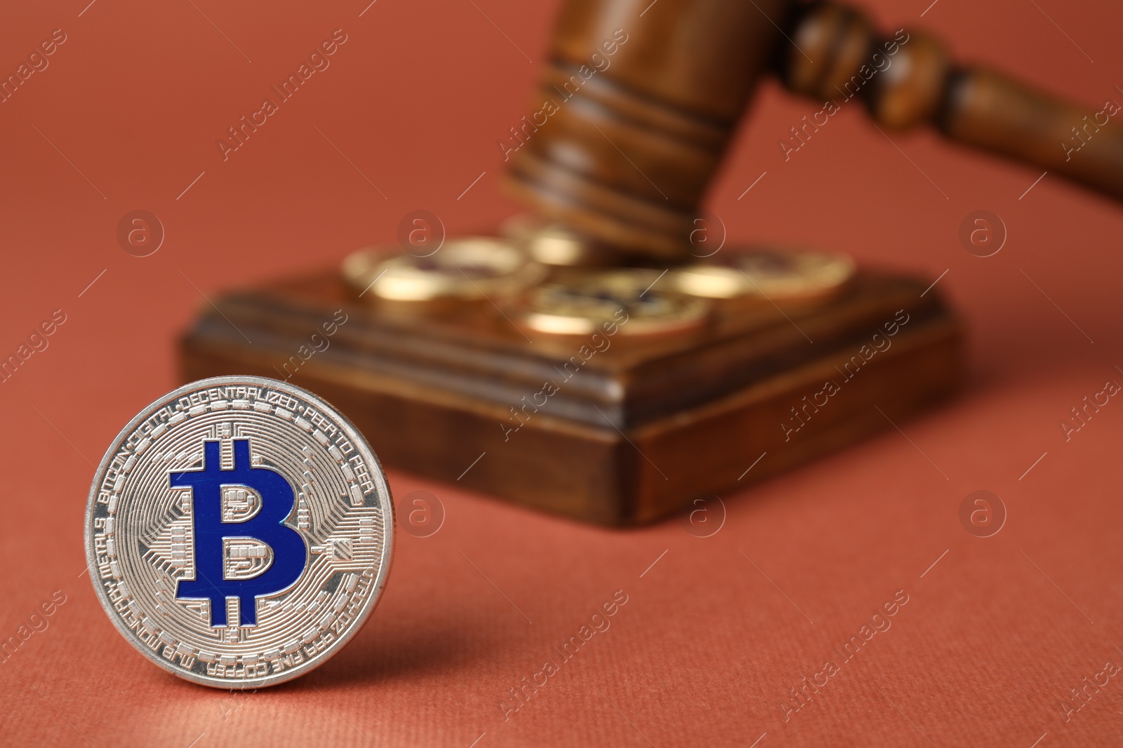 Photo of Cryptocurrency. Bitcoins and judge's gavel on red-brown background, closeup