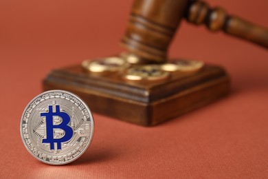 Photo of Cryptocurrency. Bitcoins and judge's gavel on red-brown background, closeup