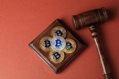 Photo of Cryptocurrency. Bitcoins and judge's gavel on red-brown background, flat lay