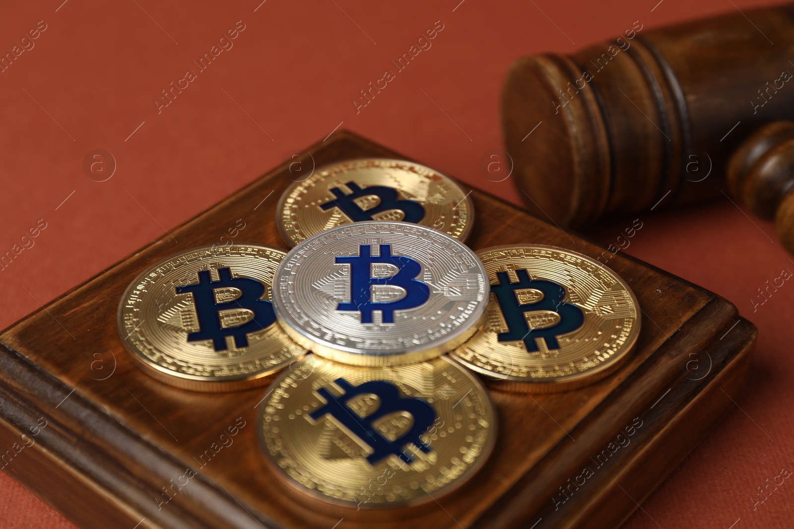Photo of Cryptocurrency. Bitcoins and judge's gavel on red-brown background, closeup