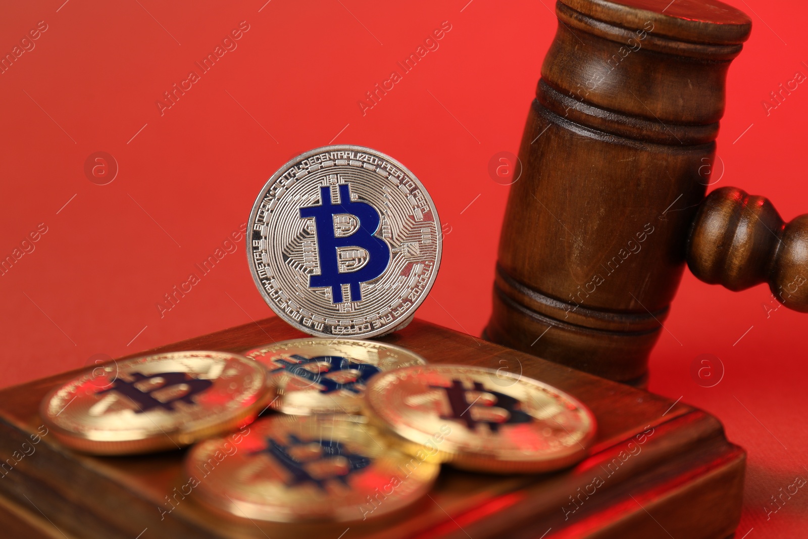Cryptocurrency. Bitcoins and judge's gavel on red background, closeup Photo of Cryptocurrency. Bitcoins and judge's gavel on red background, closeup