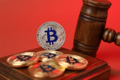 Photo of Cryptocurrency. Bitcoins and judge's gavel on red background, closeup
