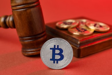 Photo of Cryptocurrency. Bitcoins and judge's gavel on red background, closeup