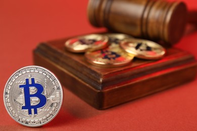 Photo of Cryptocurrency. Bitcoins and judge's gavel on red background, closeup