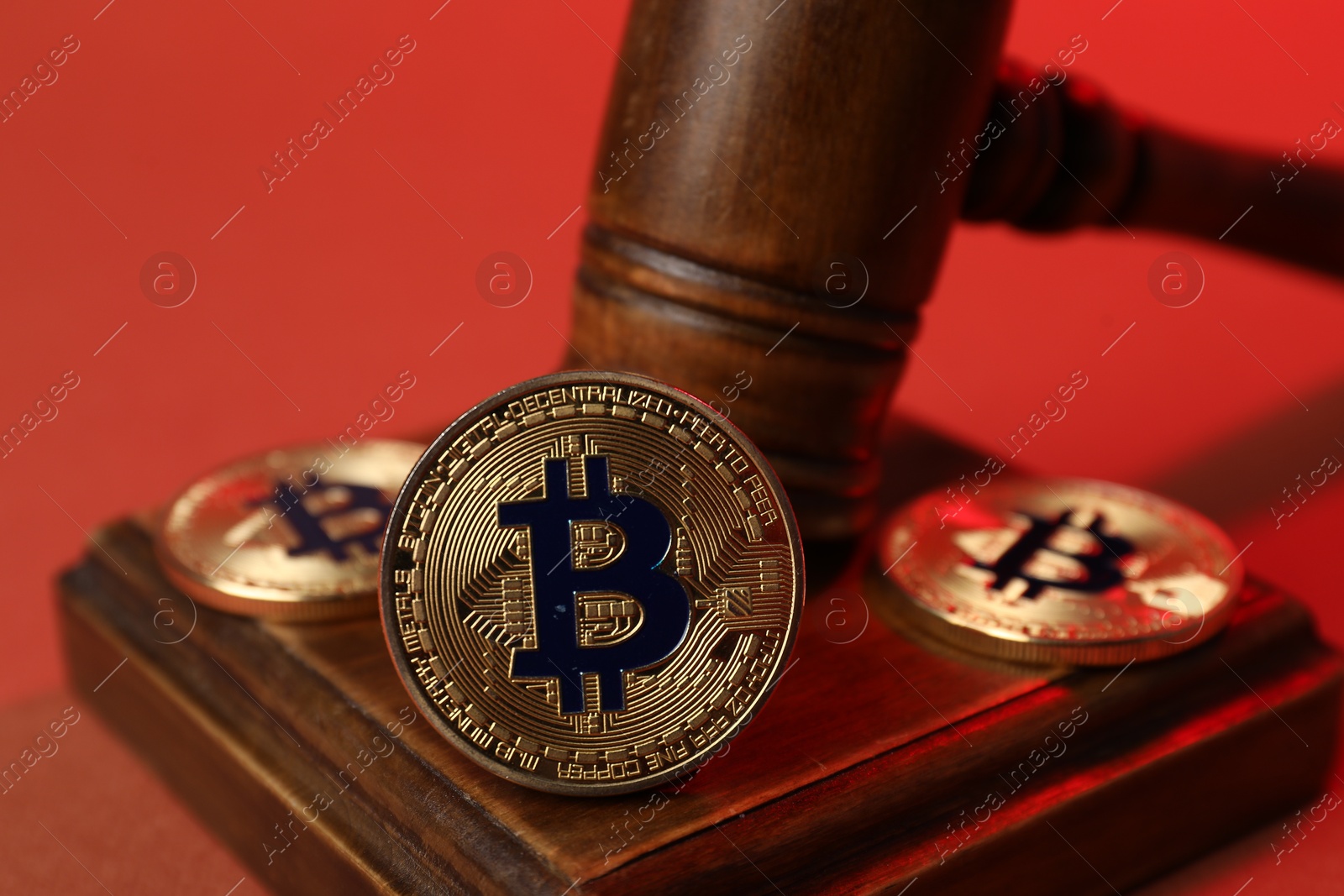 Cryptocurrency. Bitcoins and judge's gavel on red background, closeup Photo of Cryptocurrency. Bitcoins and judge's gavel on red background, closeup