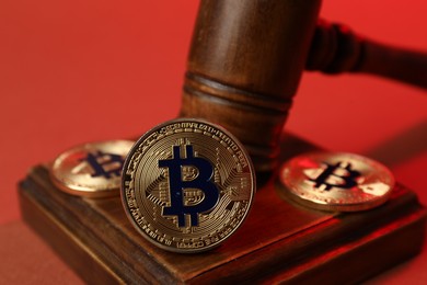 Photo of Cryptocurrency. Bitcoins and judge's gavel on red background, closeup
