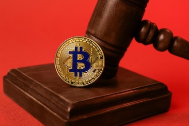 Photo of Cryptocurrency. Bitcoin and judge's gavel on red background, closeup