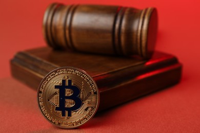 Photo of Cryptocurrency. Bitcoin and judge's gavel on red background, closeup