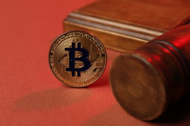 Photo of Cryptocurrency. Bitcoin and judge's gavel on red background, closeup
