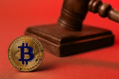 Photo of Cryptocurrency. Bitcoin and judge's gavel on red background, closeup