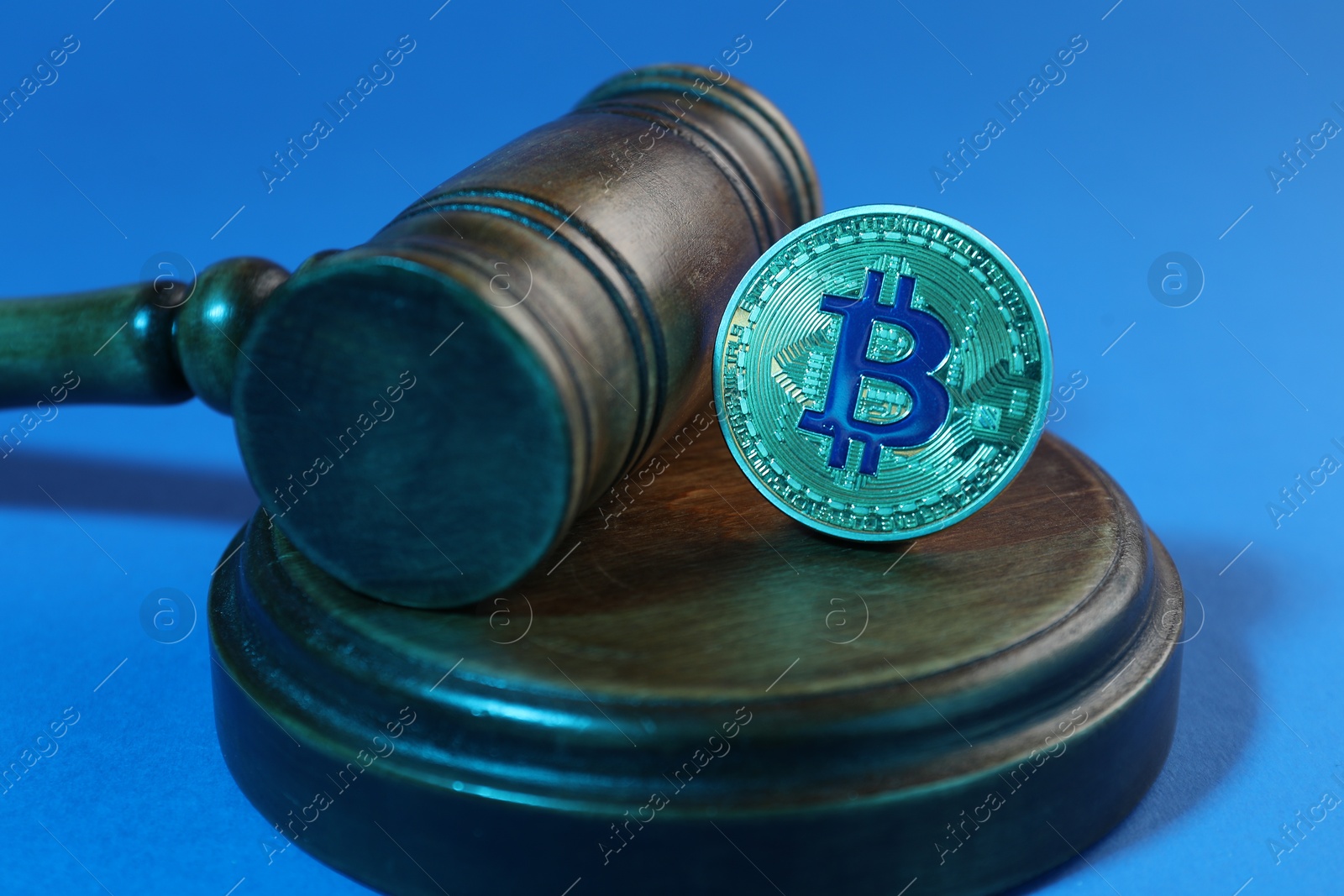 Photo of Cryptocurrency. Bitcoin and judge's gavel on light blue background, closeup. Color toned effect
