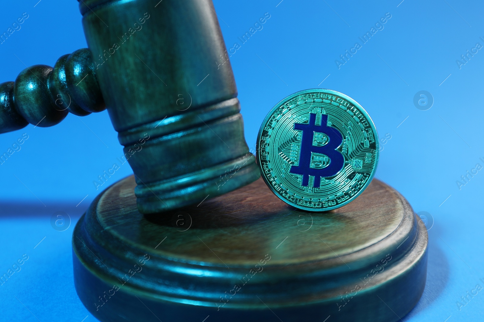 Photo of Cryptocurrency. Bitcoin and judge's gavel on light blue background, closeup. Color toned effect