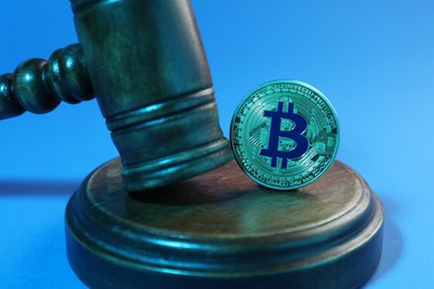 Photo of Cryptocurrency. Bitcoin and judge's gavel on light blue background, closeup. Color toned effect