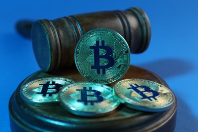 Photo of Cryptocurrency. Bitcoins and judge's gavel on light blue background, closeup. Color toned effect