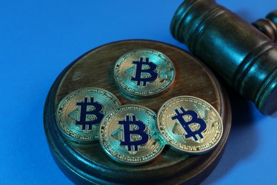 Photo of Cryptocurrency. Bitcoins and judge's gavel on light blue background, closeup. Color toned effect