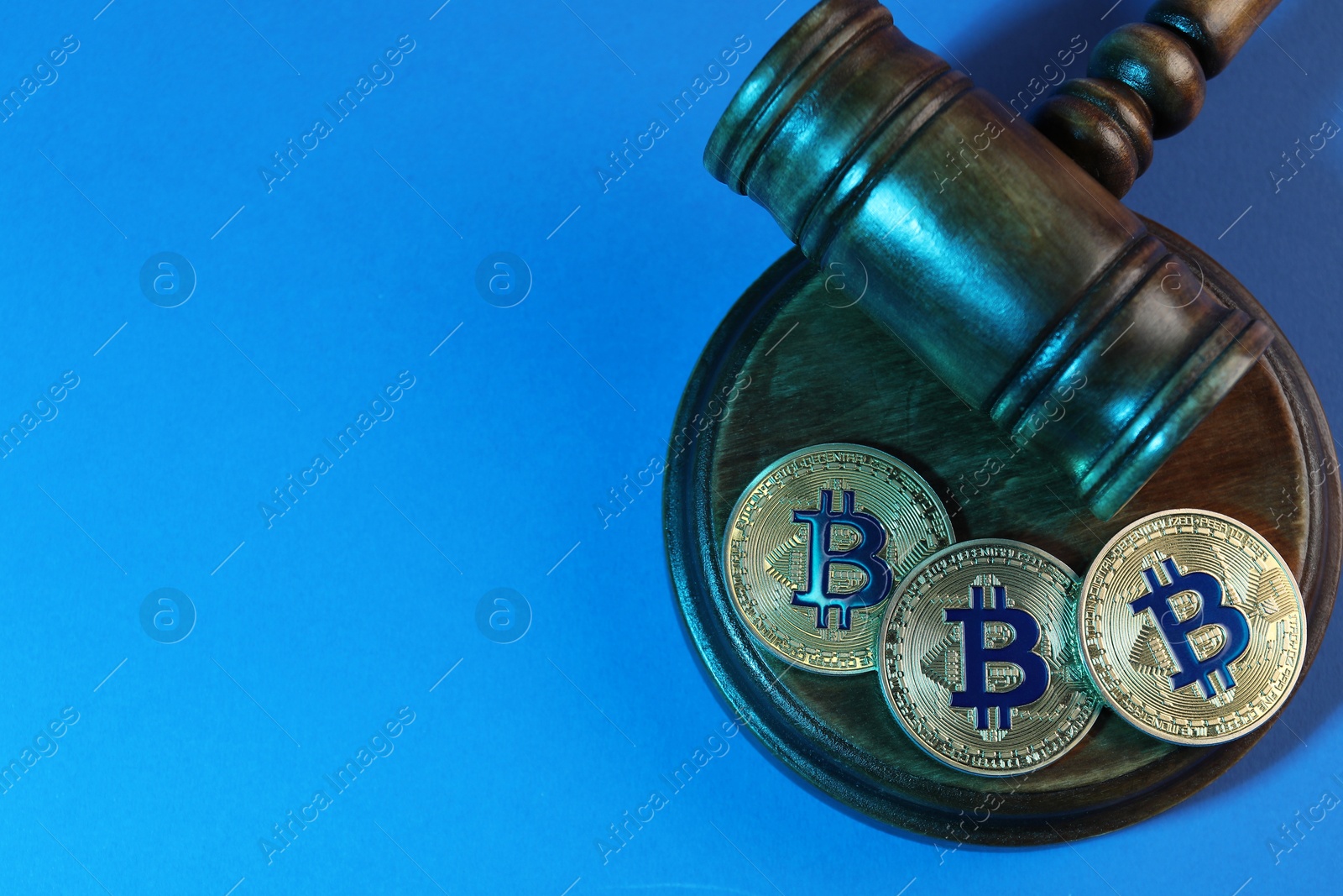 Photo of Cryptocurrency. Bitcoins and judge's gavel on light blue background, top view. Color toned effect