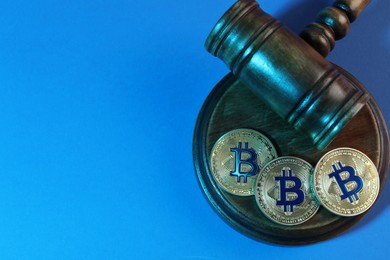 Photo of Cryptocurrency. Bitcoins and judge's gavel on light blue background, top view. Color toned effect