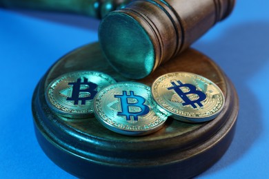Photo of Cryptocurrency. Bitcoins and judge's gavel on light blue background, closeup. Color toned effect