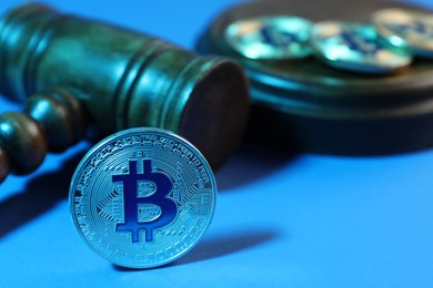 Photo of Cryptocurrency. Bitcoins and judge's gavel on light blue background, closeup. Color toned effect