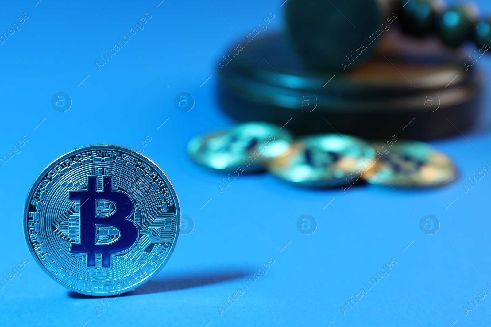 Photo of Cryptocurrency. Bitcoins and judge's gavel on light blue background, closeup. Color toned effect