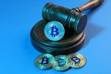 Photo of Cryptocurrency. Bitcoins and judge's gavel on light blue background, closeup. Color toned effect