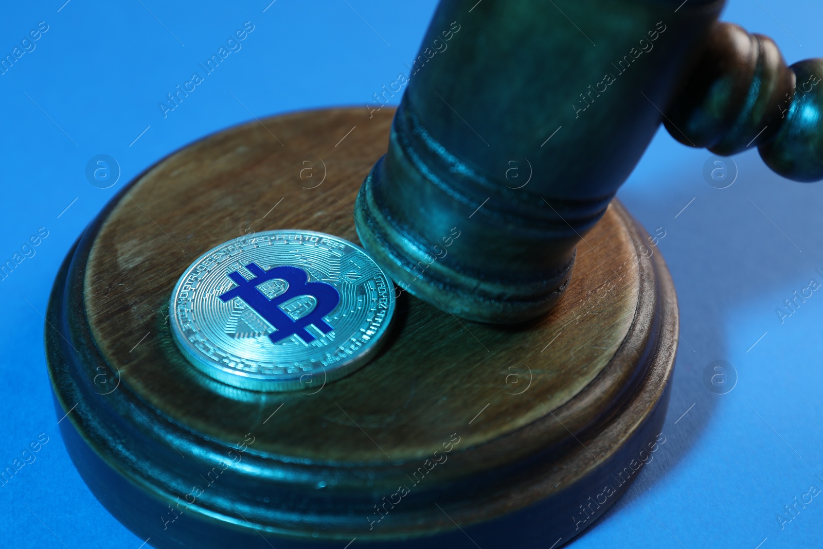 Photo of Cryptocurrency. Bitcoin and judge's gavel on light blue background, closeup. Color toned effect
