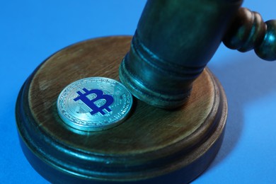 Photo of Cryptocurrency. Bitcoin and judge's gavel on light blue background, closeup. Color toned effect