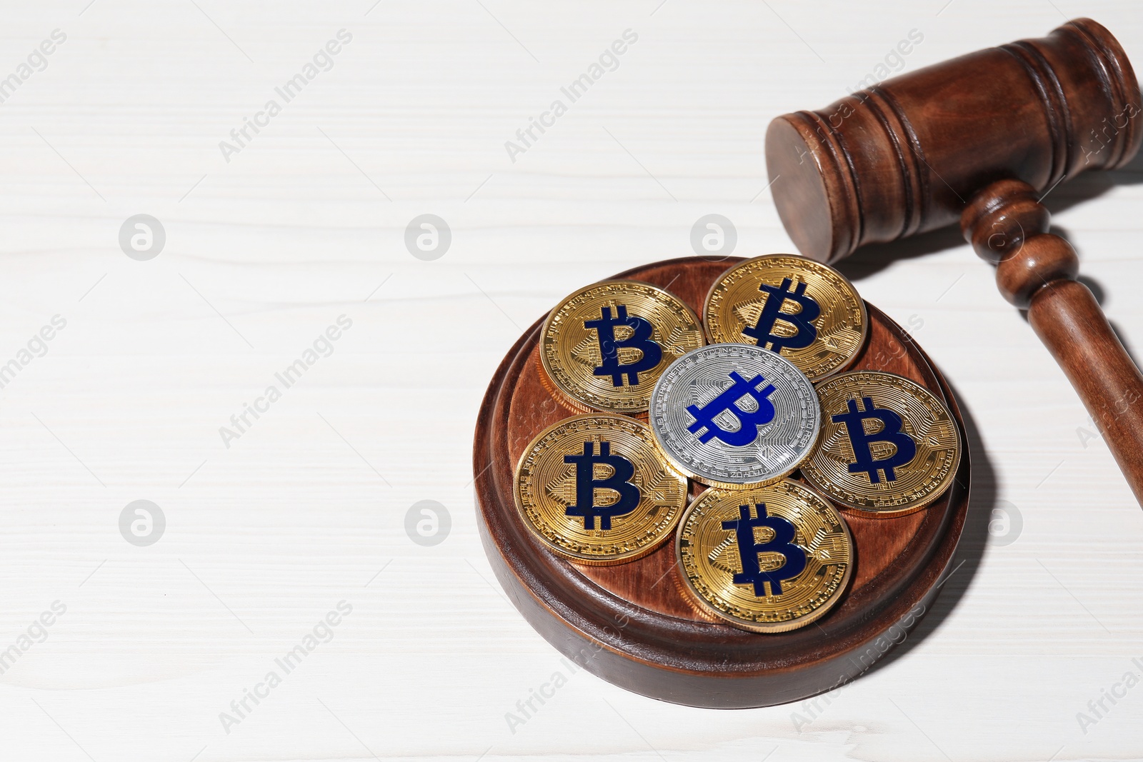 Photo of Cryptocurrency. Bitcoins and judge's gavel on white wooden table, above view. Space for text