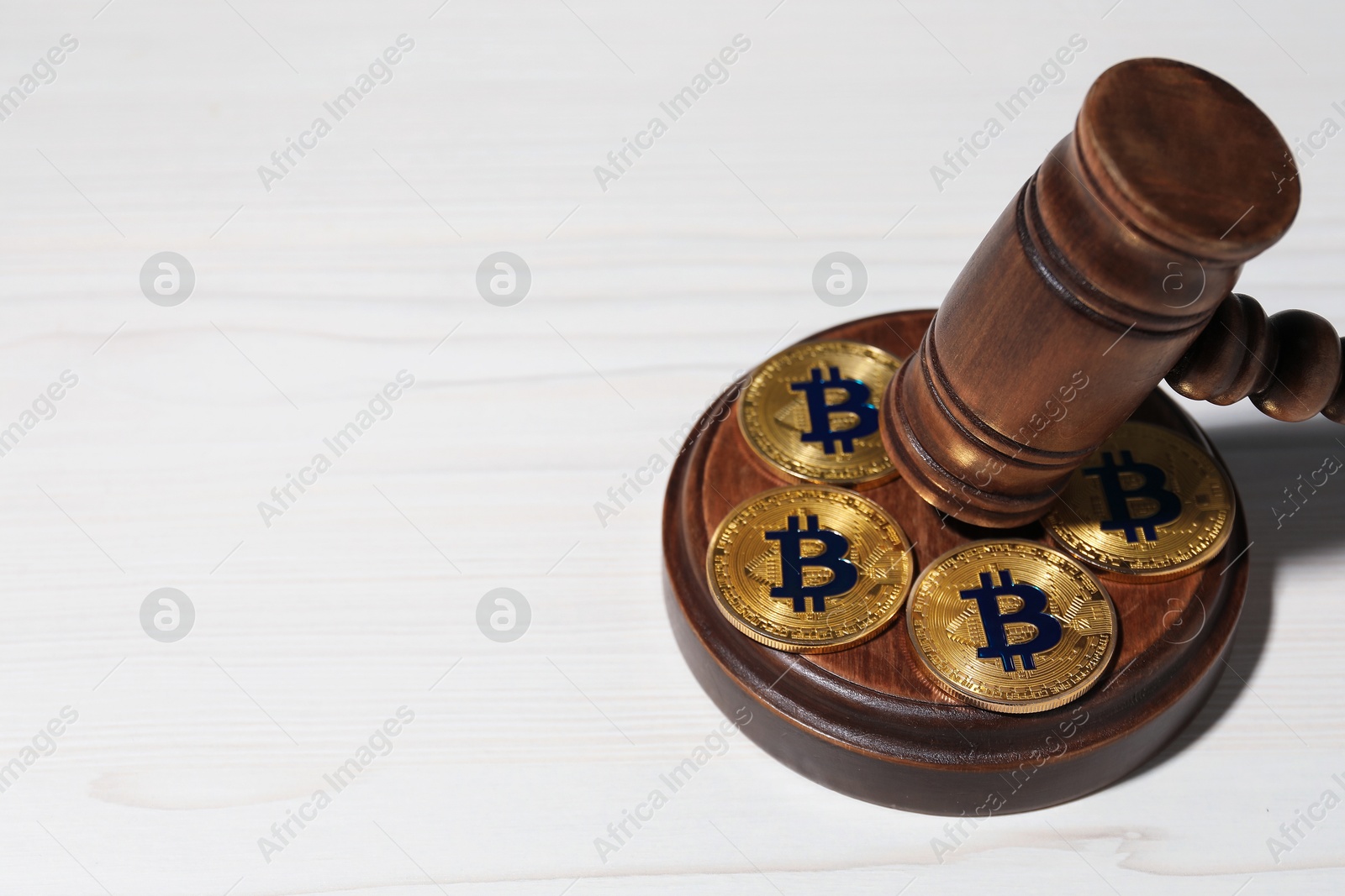 Photo of Cryptocurrency. Bitcoins and judge's gavel on white wooden table, closeup. Space for text